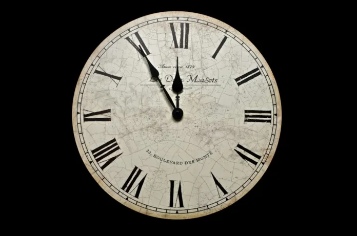 A round wall clock with a cracked white face and black Roman numerals